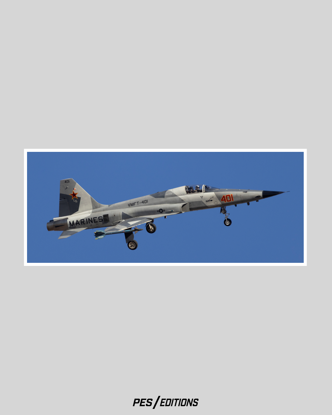 U.S. Marine Corps F-5N Tiger II adversary aircraft from VMFT-401, marked with a red star on the tail and nose number 401, flying with landing gear deployed against a clear blue sky.