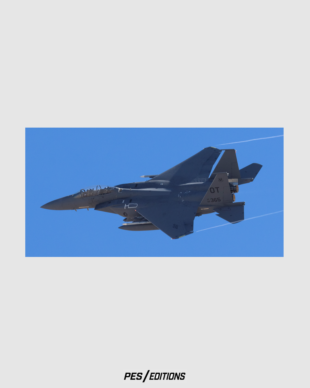 A dynamic, close-up photograph of a U.S. Air Force F-15E Strike Eagle, tail code “OT” and serial number “92-365” from the 422nd Test and Evaluation Squadron (“Green Bats”).